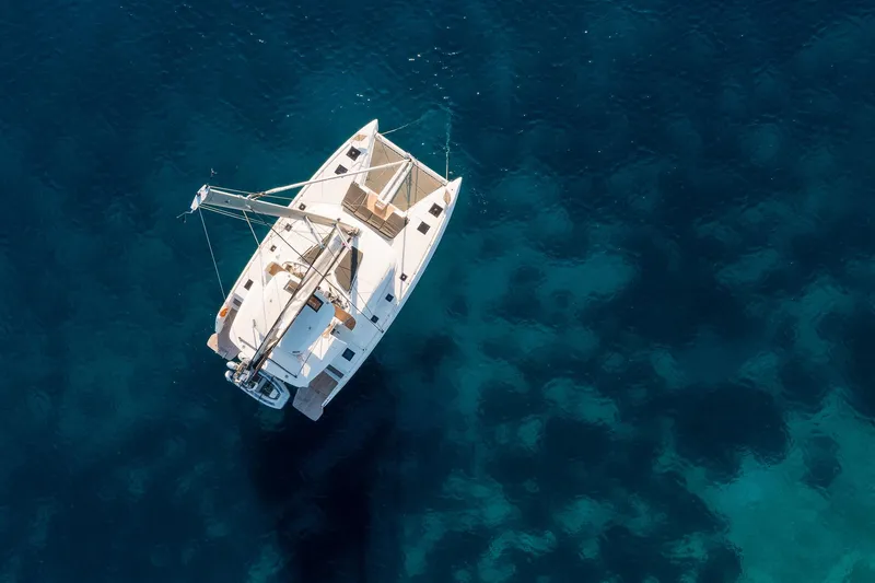 Catwalk Yacht Photos Pics Aerial view of 2023 Lagoon LAGOON 51 catamaran sailing on clear blue water.