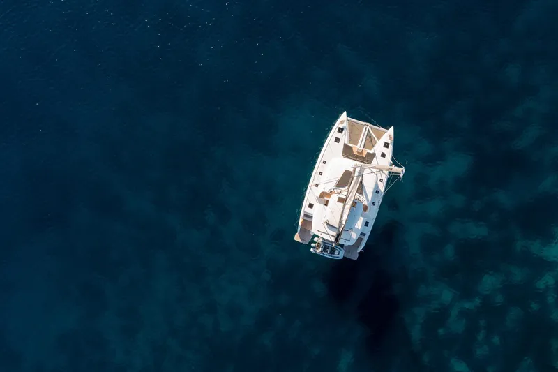 Catwalk Yacht Photos Pics Aerial view of 2023 Lagoon LAGOON 51 catamaran sailing on deep blue water.