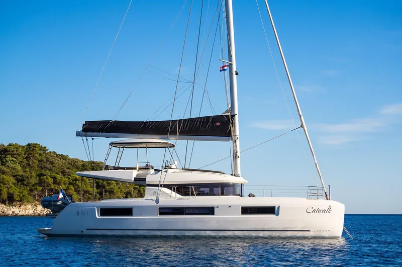 Catwalk Yacht Photos Pics 2023 Lagoon 51 catamaran sailing on calm blue waters under clear skies.
