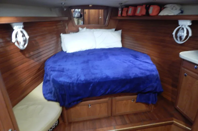  Yacht Photos Pics Cozy cabin interior of 2010 Hunter Sailing Diver with blue bedding and wooden finish.