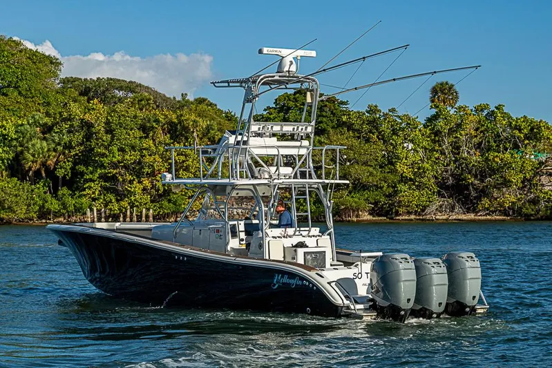  Yacht Photos Pics 2010 Yellowfin 42 Offshore boat cruising on a scenic waterway with lush greenery.