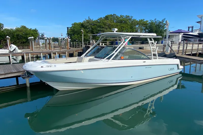  Yacht Photos Pics 2019 Boston Whaler 270 Vantage boat docked in a marina, reflecting on calm water.