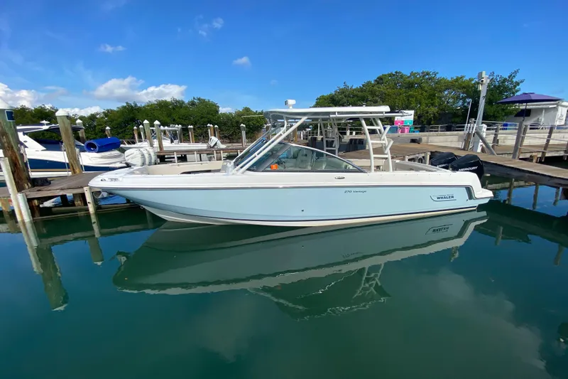  Yacht Photos Pics 2019 Boston Whaler 270 Vantage boat docked in a marina, reflecting on calm water.