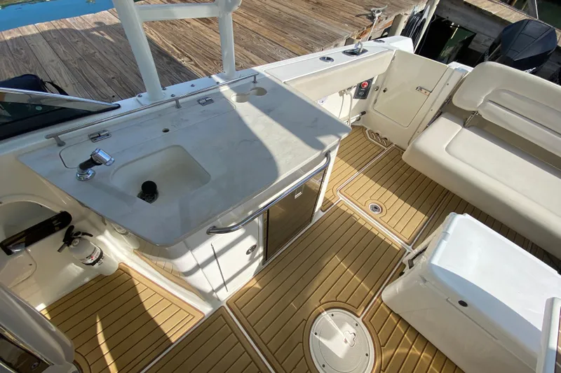 Yacht Photos Pics 2019 Boston Whaler 270 Vantage boat interior with sink, seating, and wooden deck.