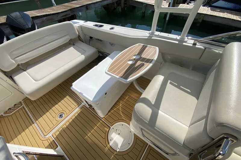  Yacht Photos Pics 2019 Boston Whaler 270 Vantage interior with seating and table, docked by water.