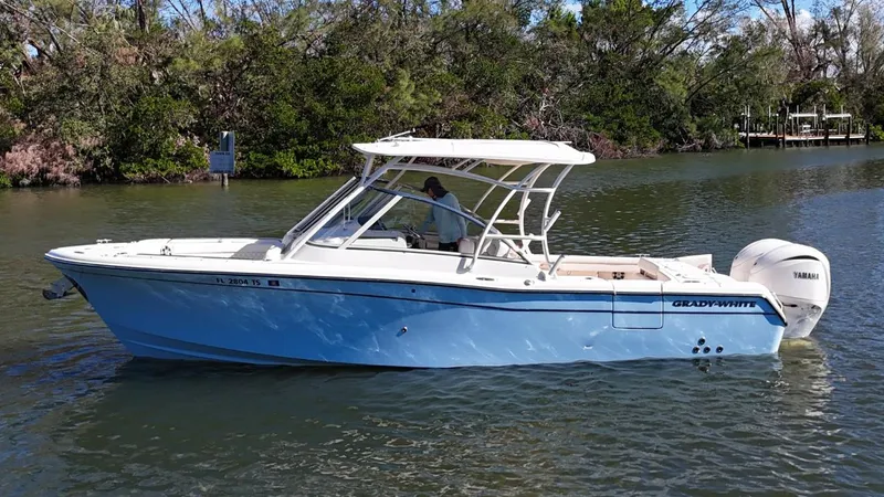  Yacht Photos Pics 2024 Grady-White Freedom 285 boat cruising on a calm river with lush greenery.