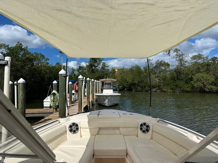  Yacht Photos Pics 2024 Grady-White Freedom 285 boat docked, featuring spacious seating and canopy, surrounded by lush greenery.