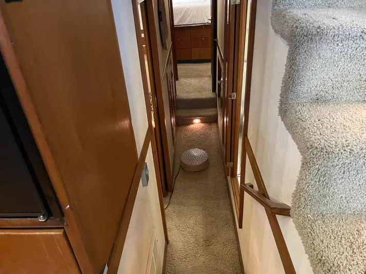 "harmony" Yacht Photos Pics Interior hallway of 1995 Bayliner 4788 Pilot House Motoryacht with carpeted stairs and wooden cabinetry.