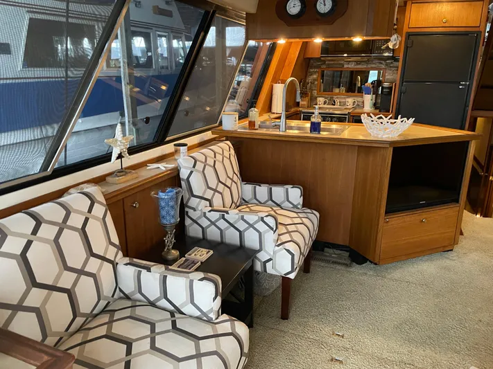 "harmony" Yacht Photos Pics Interior of 1995 Bayliner 4788 Pilot House Motoryacht with patterned chairs and wooden cabinetry.