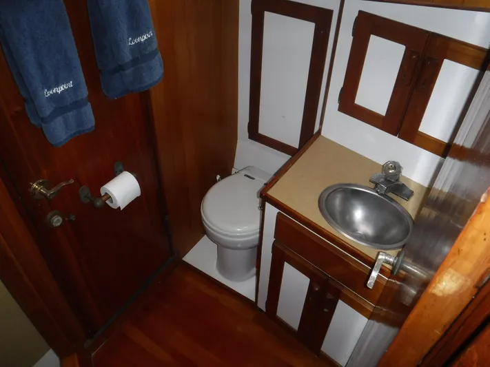 " Loon Point " Yacht Photos Pics Compact bathroom in 1986 Custom 48 Trawler with sink, toilet, and wooden cabinetry.