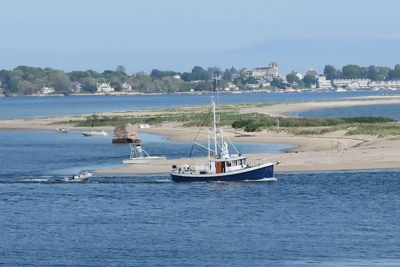 " Loon Point " Yacht Photos Pics 1986 Custom 48 Trawler navigating coastal waters near sandy shoreline and distant buildings.