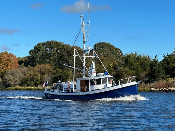 " Loon Point " Yacht Photos Pics Custom 48 Trawler boat from 1986 cruising on a scenic river under a clear blue sky.