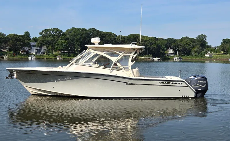  Yacht Photos Pics 2017 Grady-White Freedom 335 boat on calm water, surrounded by trees and houses.