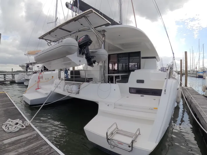 Oceanfront Yacht Photos Pics 2019 Lagoon 42 catamaran docked, featuring spacious deck and mounted dinghy.