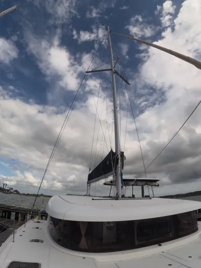 Oceanfront Yacht Photos Pics 2019 Lagoon 42 catamaran with sails, under a partly cloudy sky.