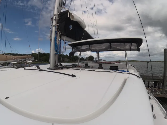 Oceanfront Yacht Photos Pics 2019 Lagoon 42 catamaran docked, featuring sleek deck and sail, under partly cloudy sky.