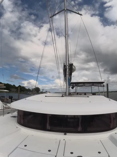 Oceanfront Yacht Photos Pics 2019 Lagoon 42 catamaran with sails, under a cloudy sky, docked by the shore.