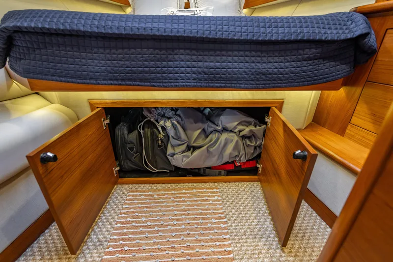 Date Night Yacht Photos Pics Under-bed storage in 2020 Palm Beach Motor Yachts PB50, featuring wooden cabinets and cozy bedding.