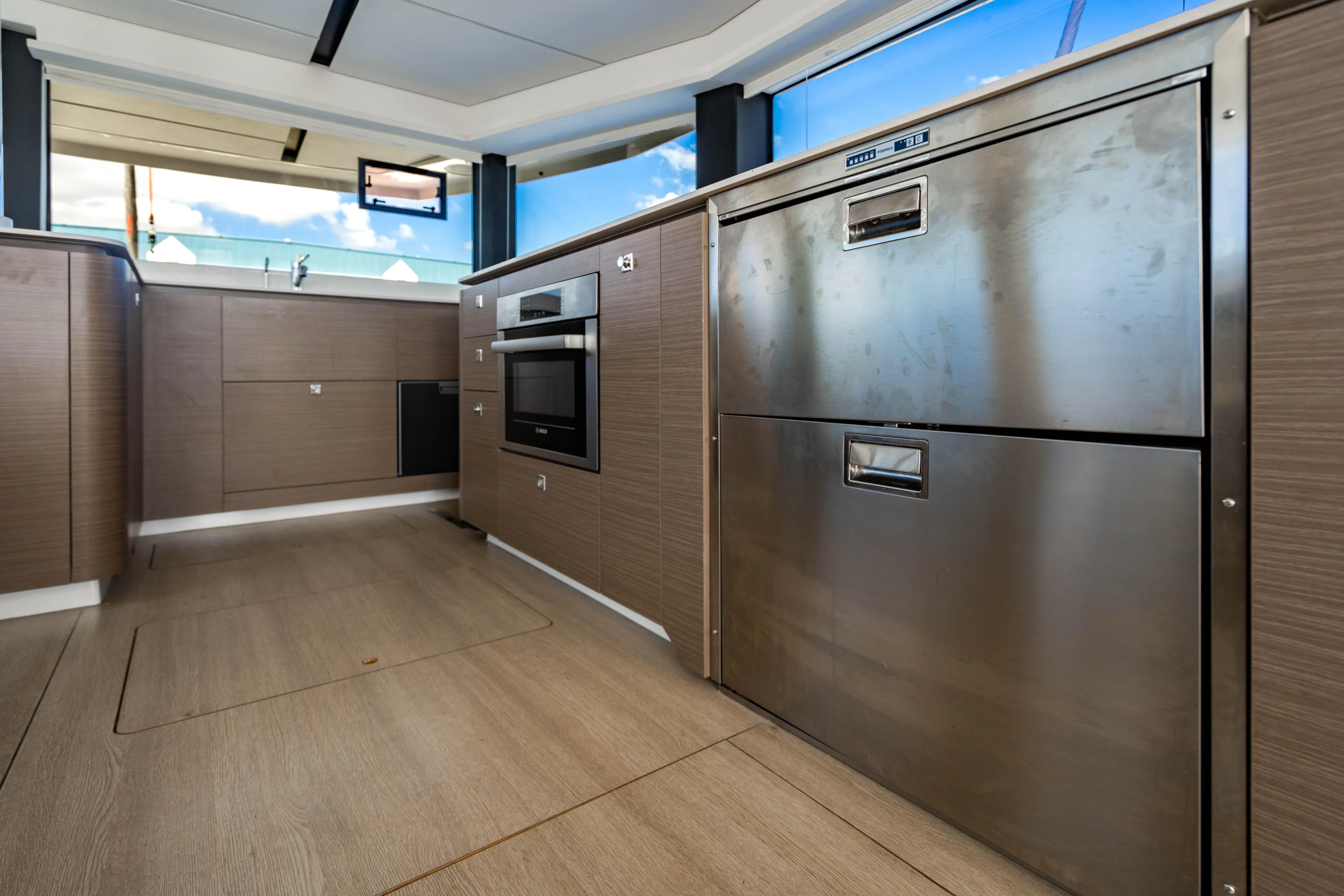 C1022 Yacht Photos Pics Modern kitchen interior on 2025 Leopard 46 yacht, featuring stainless steel appliances and wood cabinetry.