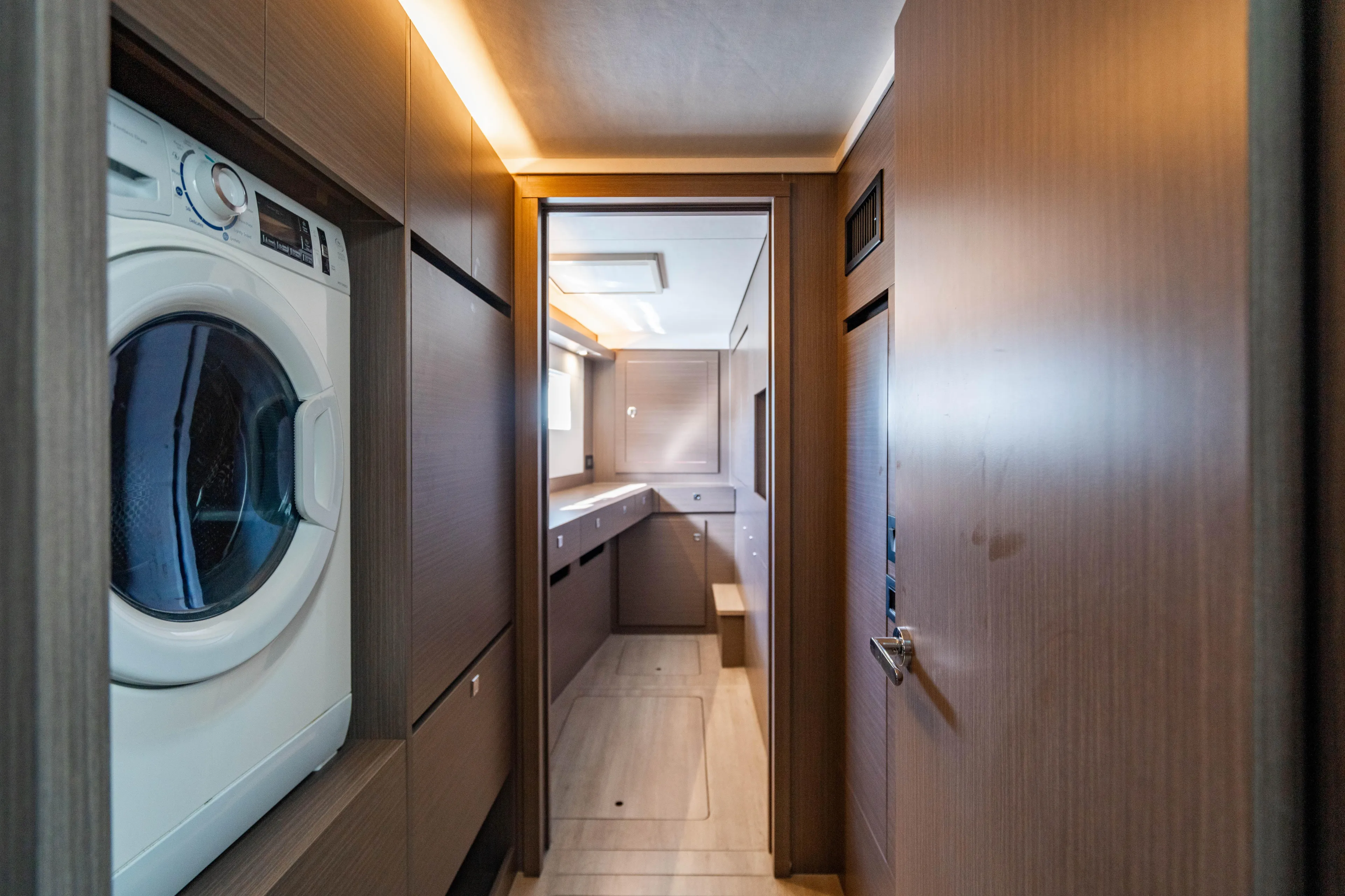 C1022 Yacht Photos Pics Modern laundry area inside 2025 Leopard 46 yacht, featuring sleek wood paneling and washer.