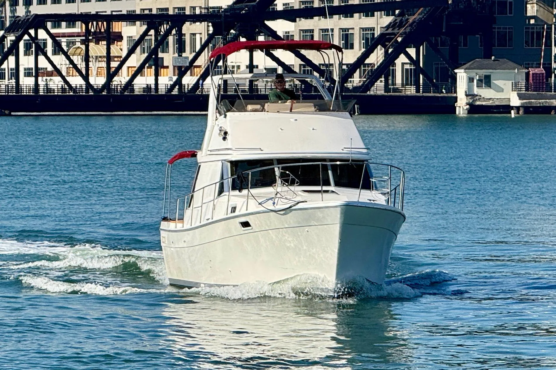 1989 Bayliner 3288 Motoryacht cruising on water near industrial backdrop.