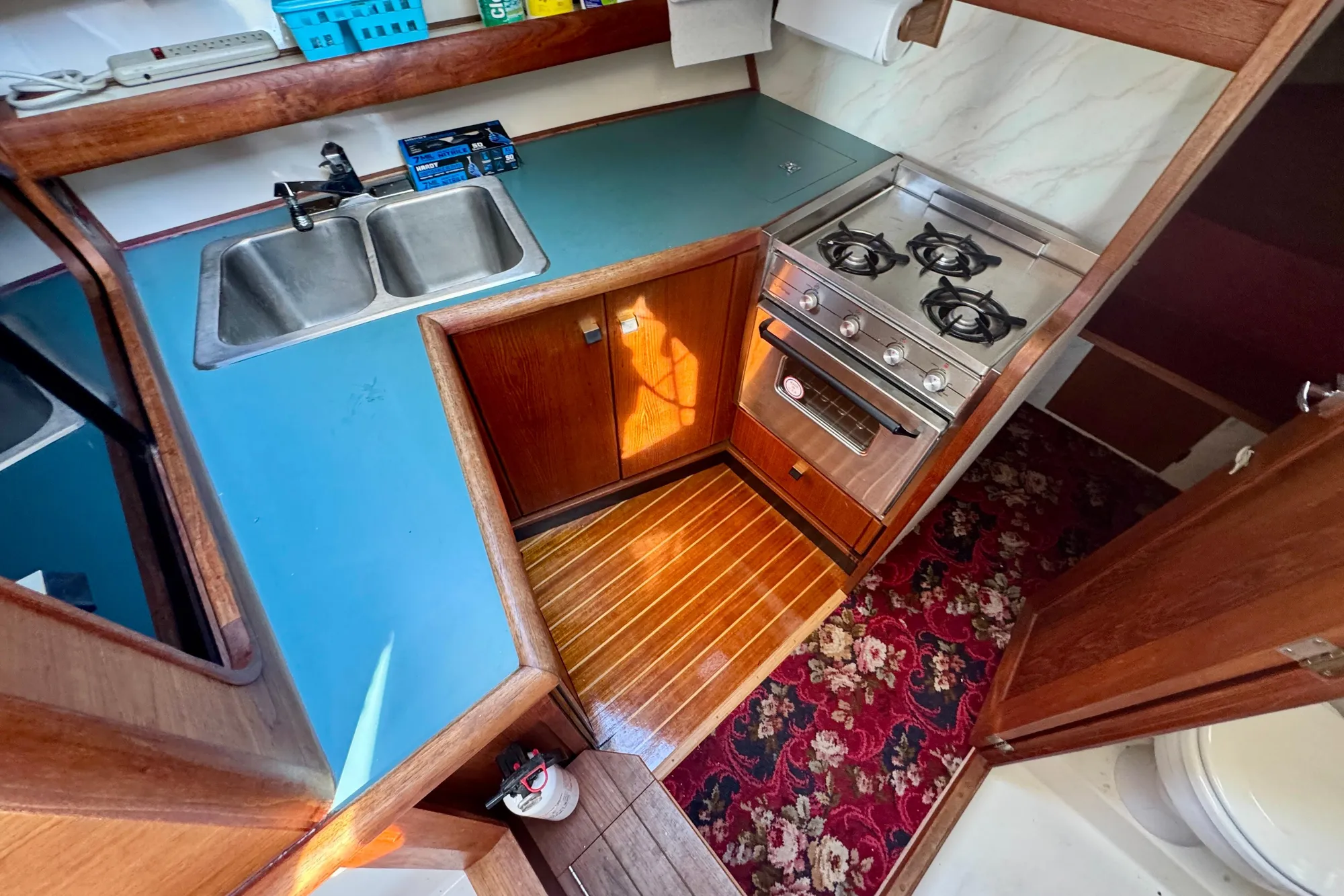 1989 Bayliner 3288 Motoryacht kitchen with stove, sink, and wooden cabinetry.