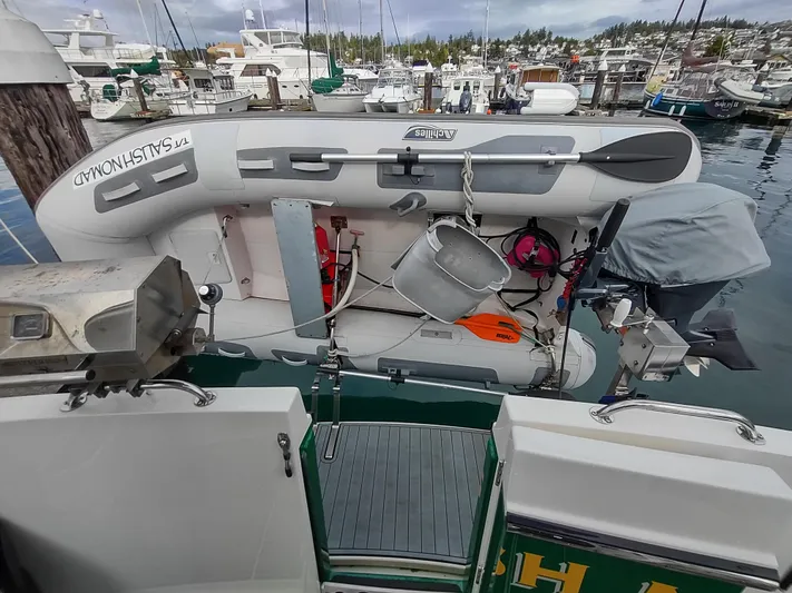 Salish Nomad Yacht Photos Pics 2007 American Tug 34 with dinghy at marina, featuring docked boats in the background.