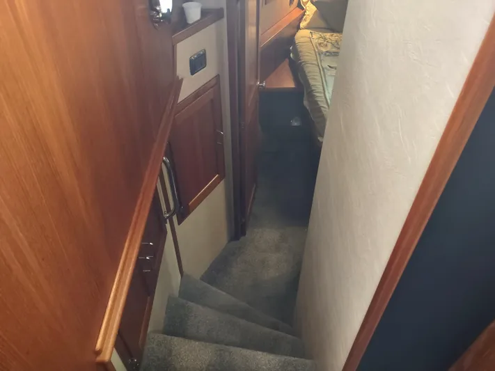 Salish Nomad Yacht Photos Pics Interior stairs of 2007 American Tug 34 with carpet and wood paneling.