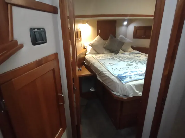 Salish Nomad Yacht Photos Pics Cozy bedroom interior of 2007 American Tug 34 with wooden accents and soft lighting.