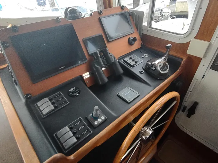 Salish Nomad Yacht Photos Pics Control panel of 2007 American Tug 34 with navigation screens and steering wheel.