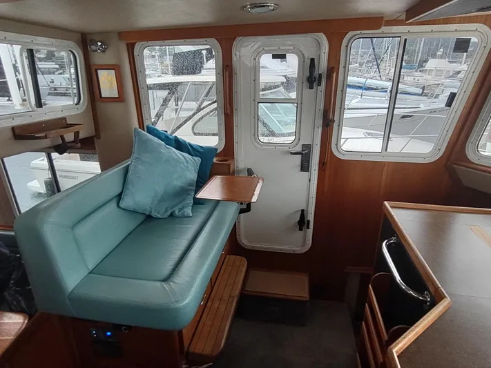 Salish Nomad Yacht Photos Pics Interior of 2007 American Tug 34 with teal seating and wooden accents.