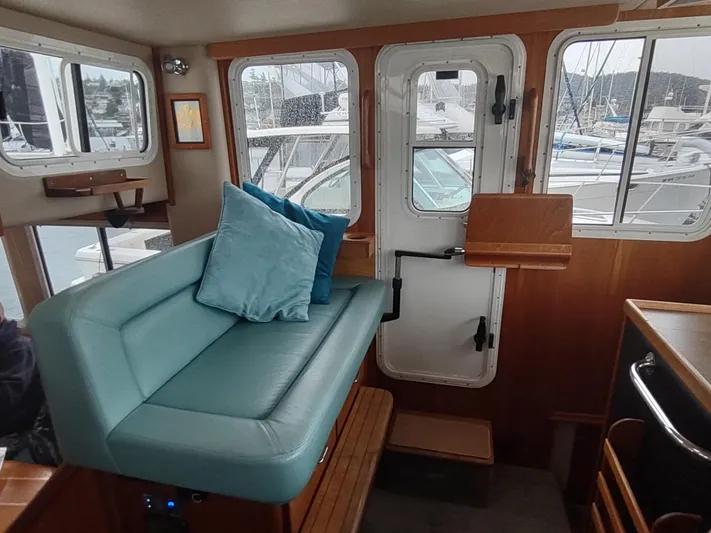 Salish Nomad Yacht Photos Pics Interior of 2007 American Tug 34 with teal seating and marina view.