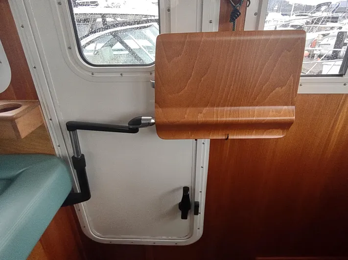 Salish Nomad Yacht Photos Pics Interior of a 2007 American Tug 34, featuring a wooden fold-out table and door.