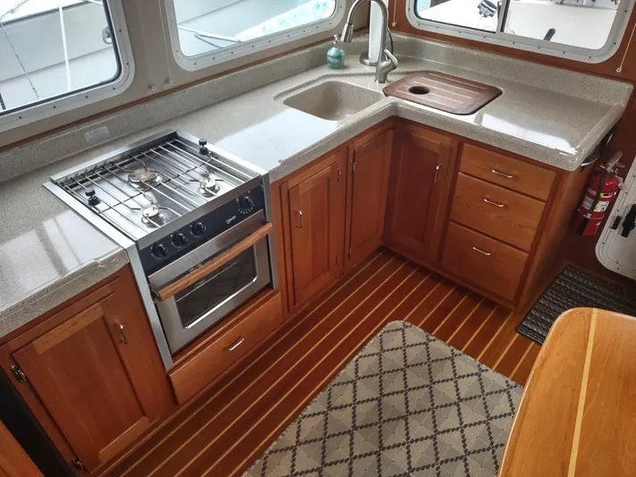 Salish Nomad Yacht Photos Pics 2007 American Tug 34 kitchen with wood cabinets, stove, and sink.