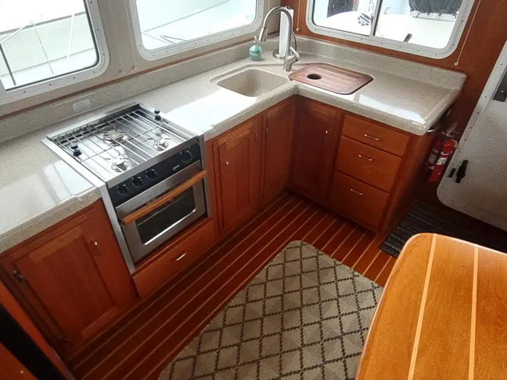 Salish Nomad Yacht Photos Pics 2007 American Tug 34 kitchen with stove, sink, wooden cabinets, and striped flooring.