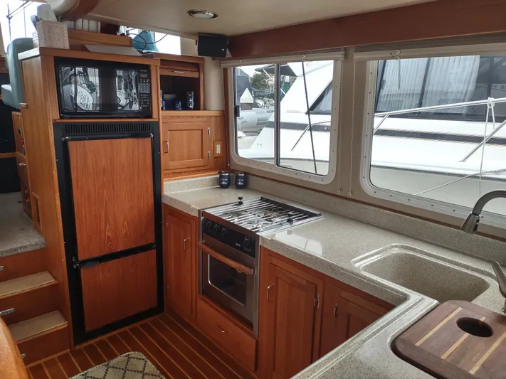 Salish Nomad Yacht Photos Pics Interior of 2007 American Tug 34 with kitchen, stove, and wooden cabinetry.