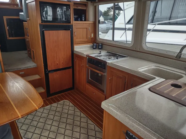 Salish Nomad Yacht Photos Pics Interior of 2007 American Tug 34, featuring a well-equipped kitchen with wood cabinetry.