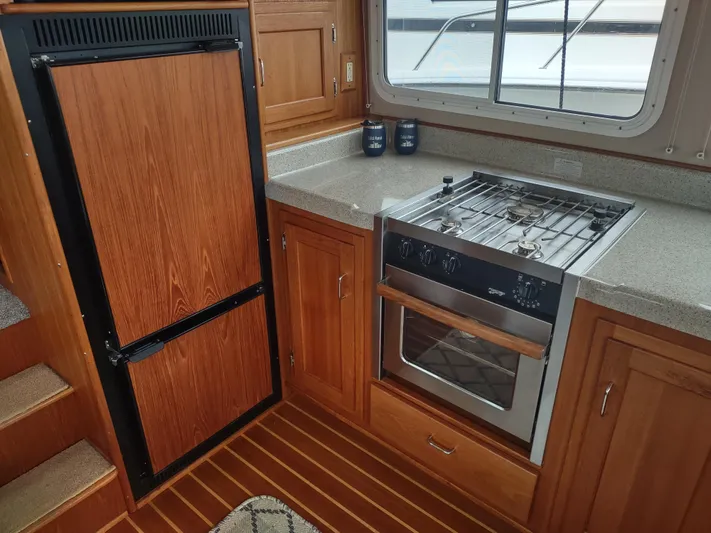 Salish Nomad Yacht Photos Pics 2007 American Tug 34 kitchen with stove, oven, and wood cabinetry.