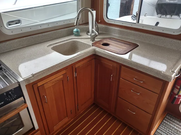 Salish Nomad Yacht Photos Pics 2007 American Tug 34 kitchen with wooden cabinets and countertop sink.