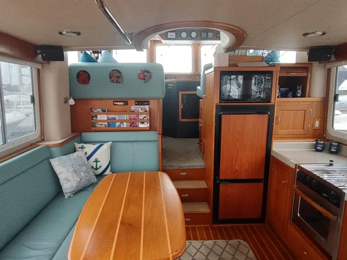 Salish Nomad Yacht Photos Pics Interior of 2007 American Tug 34, featuring cozy seating, wooden table, and modern kitchen amenities.