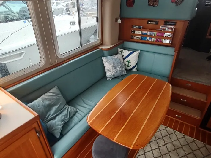 Salish Nomad Yacht Photos Pics Cozy interior of 2007 American Tug 34 with teal seating and wooden table.