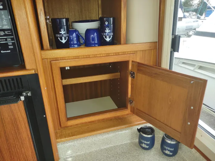Salish Nomad Yacht Photos Pics Wooden cabinet with nautical-themed mugs and bowls on an American Tug 34, 2007 model.