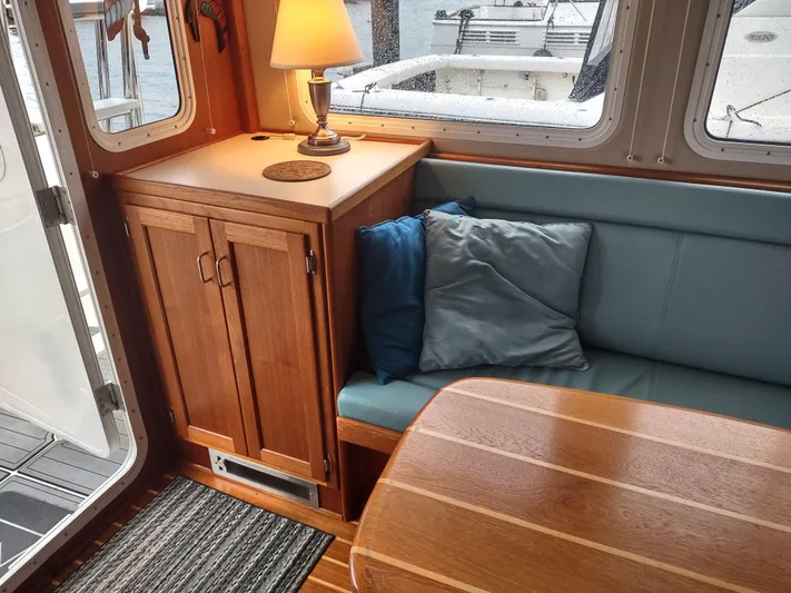 Salish Nomad Yacht Photos Pics Cozy interior of 2007 American Tug 34 with wood cabinetry and cushioned seating.