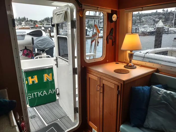Salish Nomad Yacht Photos Pics Cozy interior of 2007 American Tug 34 with lamp and marina view.