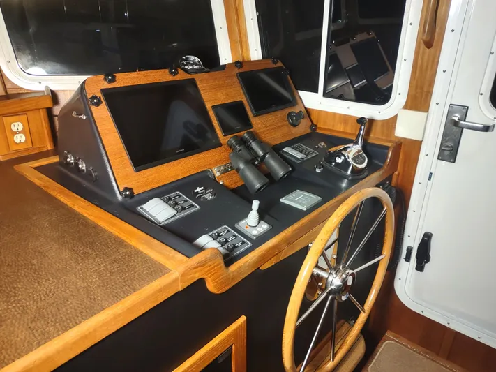 Salish Nomad Yacht Photos Pics 2007 American Tug 34 helm with navigation screens, steering wheel, and controls.