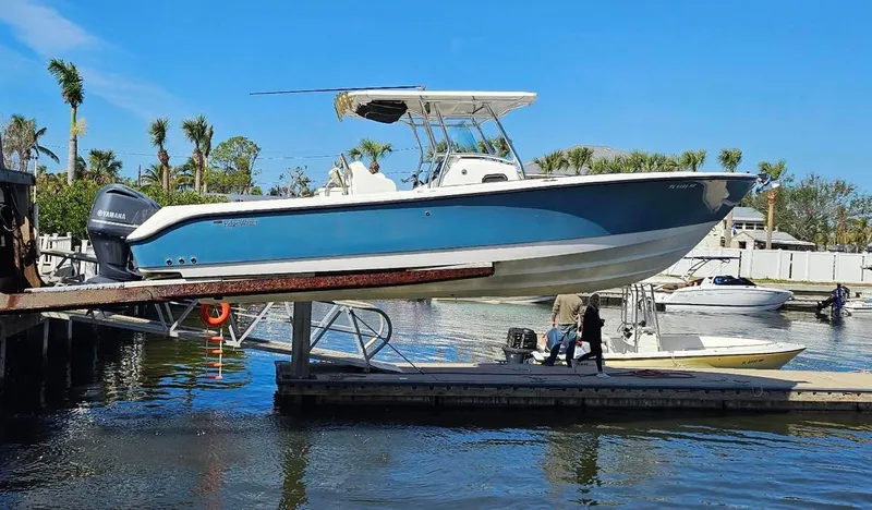  Yacht Photos Pics 2012 Edgewater 318CC boat on lift at marina, clear sky, palm trees in background.