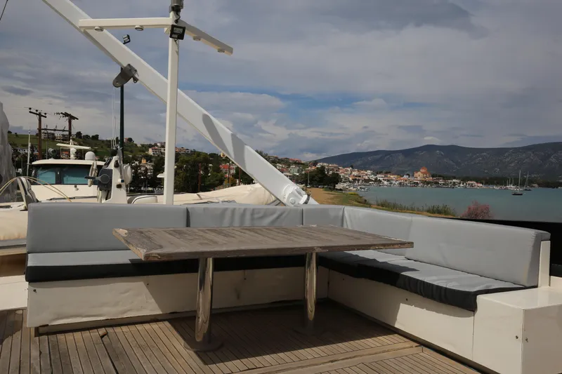  Yacht Photos Pics Outdoor seating area on a 1990 Sanlorenzo 80 yacht with scenic coastal view.