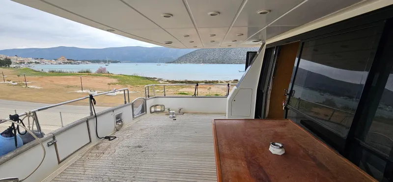  Yacht Photos Pics Deck view of 1990 Sanlorenzo 80 yacht overlooking serene coastal landscape.