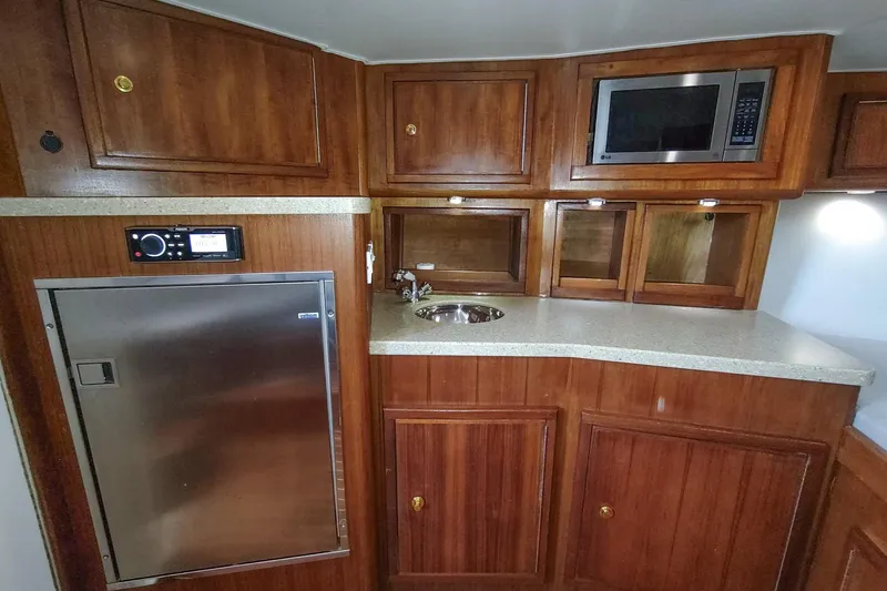 Never Enough Yacht Photos Pics 2017 Out Island SeaTek 36 Express yacht interior with wood cabinetry, microwave, and compact fridge.