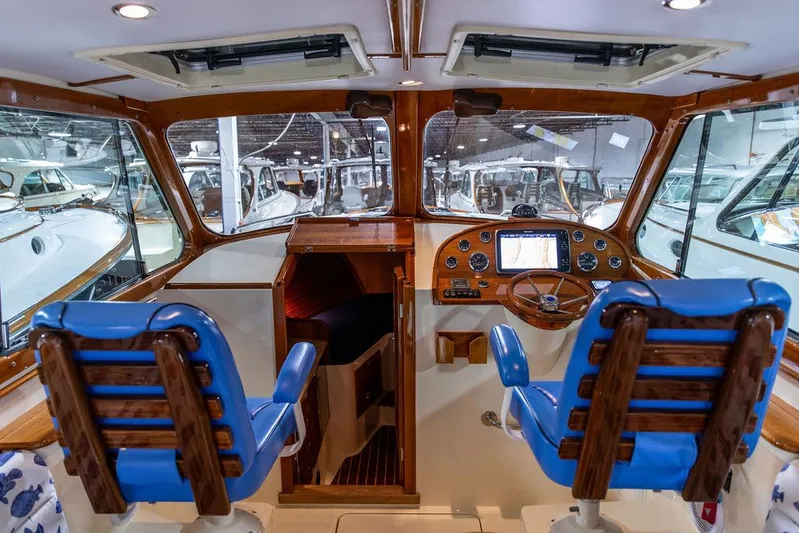 Valor Yacht Photos Pics Interior of 2014 Hinckley Talaria 34 boat with blue seats and wooden dashboard.